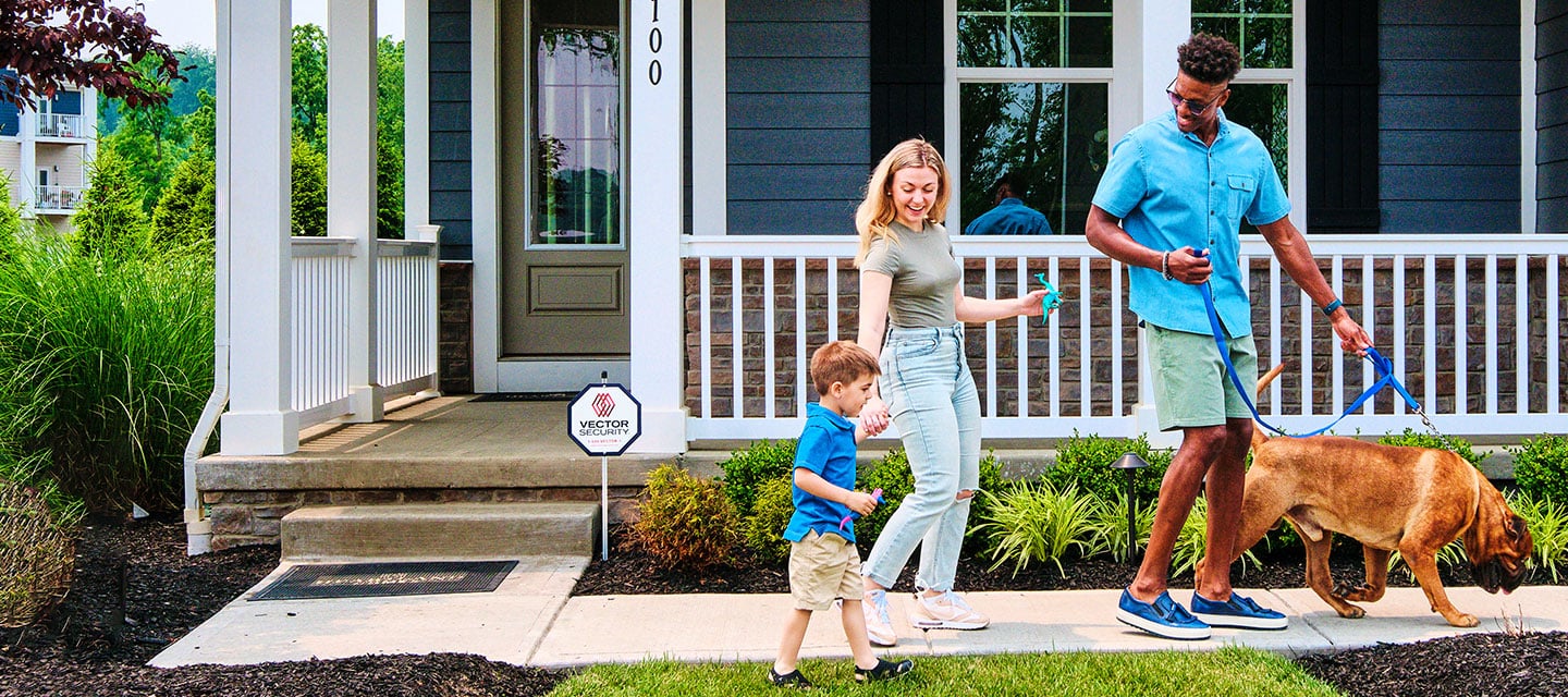 Happy family walking dog with Vector Security Yard sign.